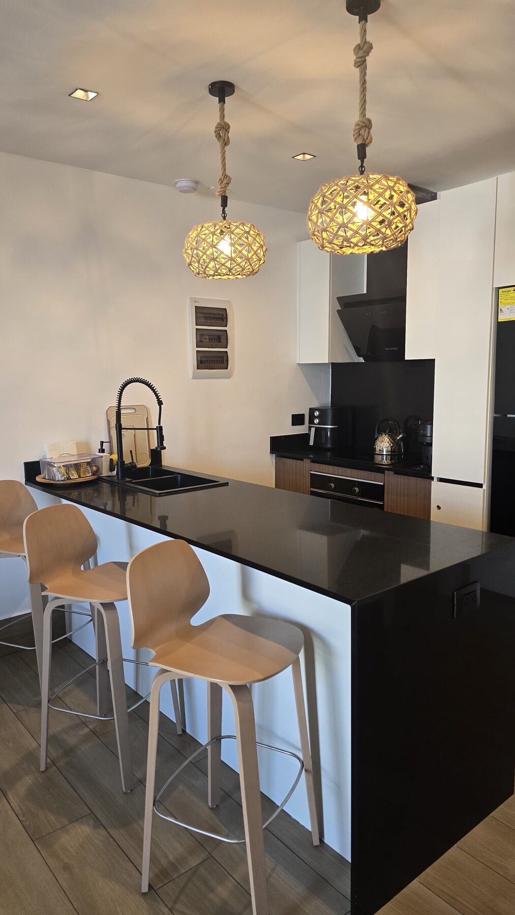 Fully equipped kitchen with black granite breakfast bar and rattan pendant lights