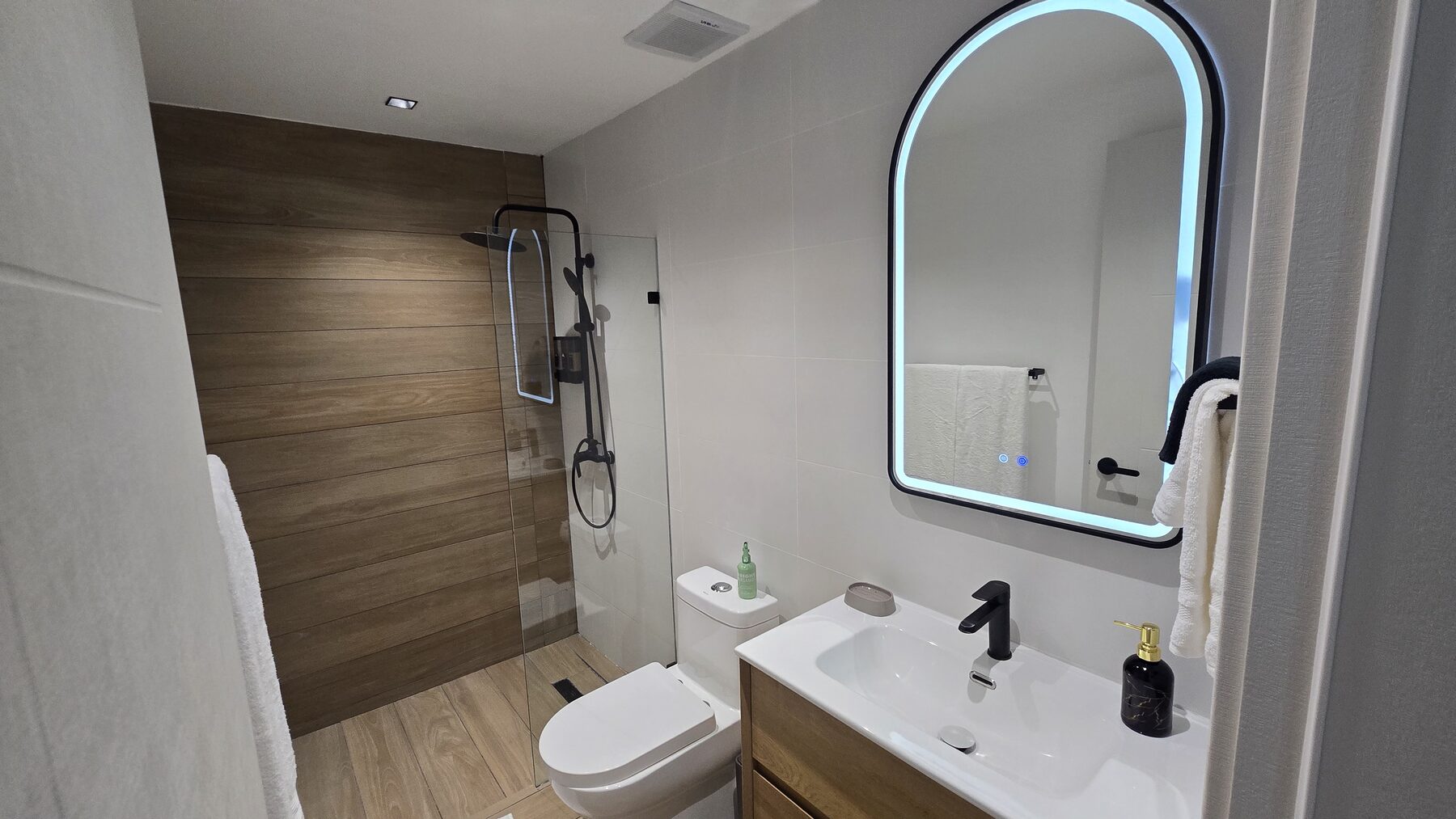 Modern bathroom with walk-in rain shower and backlit mirror