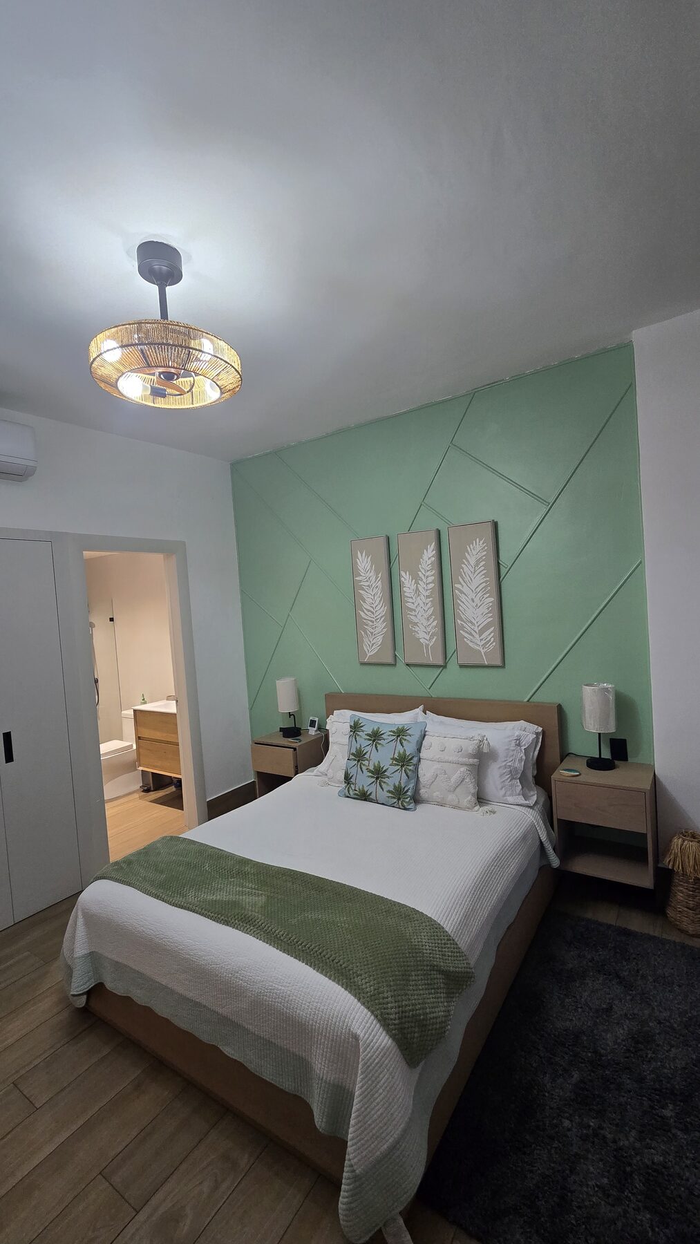 Queen bed with tropical cushions, bedside lamps and en-suite bathroom door